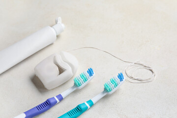 Dental floss with tooth brushes and paste on white background