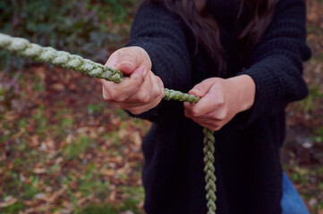 Young woman pulls hard on a hemp rope. Concept of strength, endurance, perseverance, female...