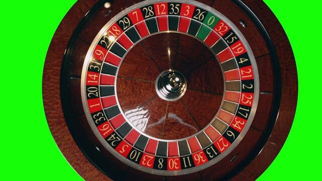 Close up of roulette wheel in motion at a green screen background. The wheel ball is spinning. Concept of casino and gambling.