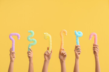 Hands with popular pop tubes on color background