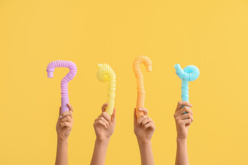 Hands with popular pop tubes on color background