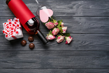 Composition with bottle of wine, chocolate candies and roses for Valentine's Day on dark wooden background