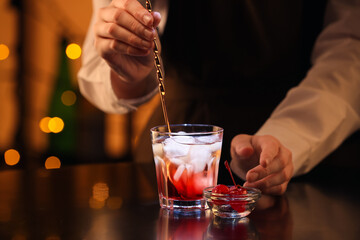 Bartender preparing tasty Manhattan cocktail at table in bar