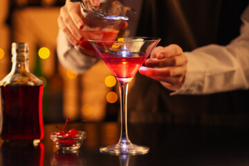 Bartender preparing tasty Manhattan cocktail at table in bar