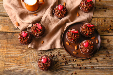 Plate with tasty chocolate cupcakes for Valentine's day, almond and coffee beans on wooden...