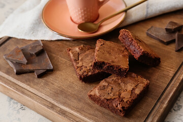 Wooden board with pieces of tasty chocolate brownie on table