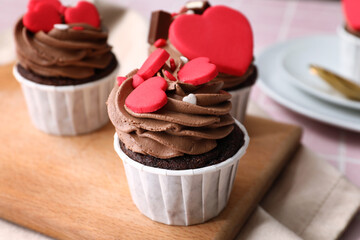Wooden board with tasty chocolate cupcakes for Valentine's Day on table