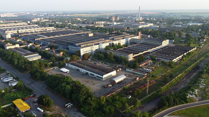 Aerial drone view flight over industrial zone on summer morning. Top view of large logistics park with factories, plants, thermoelectric power station, garages, hangars in city.