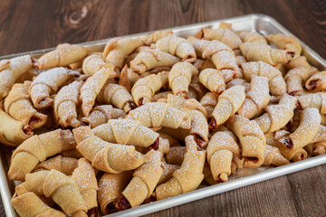 Baked crescent cookies with jam on oven tray..