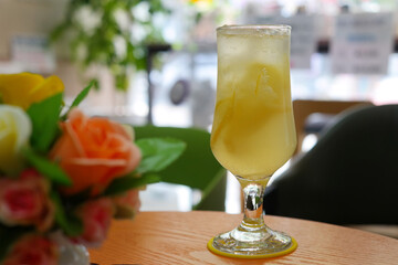 A long glass is filled with yellow ade.
