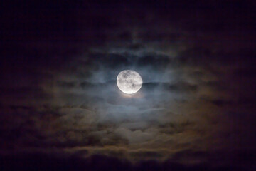 Full moon with colorful clouds in foreground