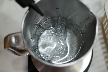 clear liquid is being poured into a stainless measuring cup.