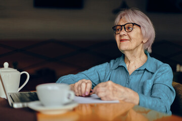 Senior woman sitting in a cafe with a cup of coffee and a laptop Social networks unaltered