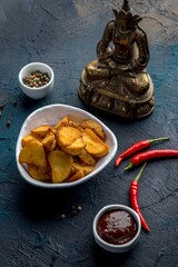 Deep-fried potato wedges with paprika and red sauce. Decorated in Asian style.