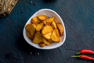 Deep-fried potato wedges with paprika and red sauce. Decorated in Asian style.