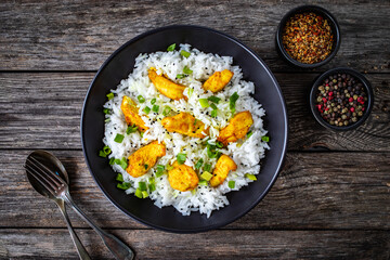 Chicken nuggets with rice and vegetables on wooden table

