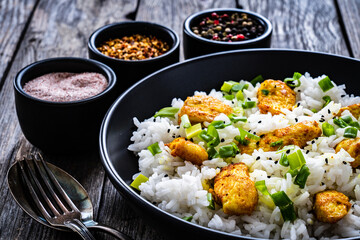 Chicken nuggets with rice and vegetables on wooden table
