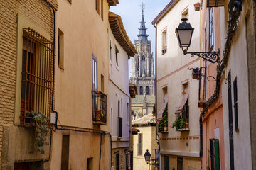 Narrow alley with old houses and view of the cathedral of Toledo in the background. Spain.