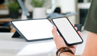 Closeup view of asian man holding in hands smartphone with empty blank mockup screen for advertising, using mobile apps. Remote e learning, online work, e commerce.