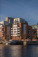 Apartment houses and a pier with sailing boats at the bay Hammarby sj&ouml; in the district S&ouml;dermalm a sunny and snowy winter day in Stockholm
