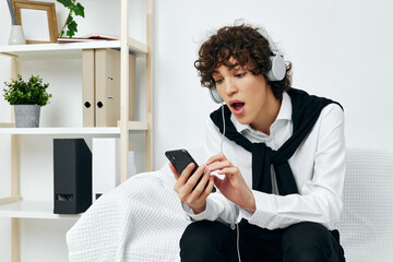 man sittingin headphones on a white sofa smartphone Lifestyle technology 