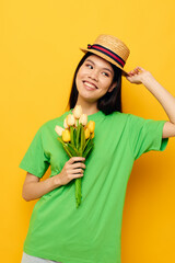 woman green t-shirt a bouquet of yellow flowers in a hat yellow background unaltered