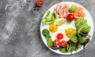 Ketogenic breakfast. Keto low carb salmon, boiled shrimps, prawns, fried eggs, fresh salad, tomatoes, cucumbers and avocado. top view. Low carb diet concept. high fat diet