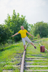 crazy traveler with a red suitcase on the rails goes