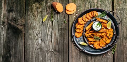 Set of homemade baked sweet potato fries with lime. Sweet potato fries with herbs on wooden background banner, menu, recipe place for text, top view