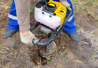 A worker is drilling soil for a gate