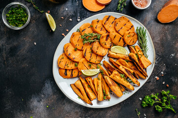 fried grilled sweet potatoes with lime on a black background. banner, menu, recipe place for text, top view