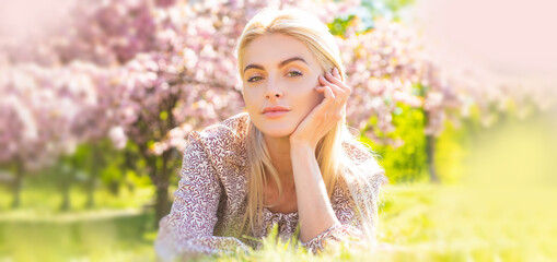 Spring woman face for banner. Beautiful girl in pink flowers in summer blossom park.