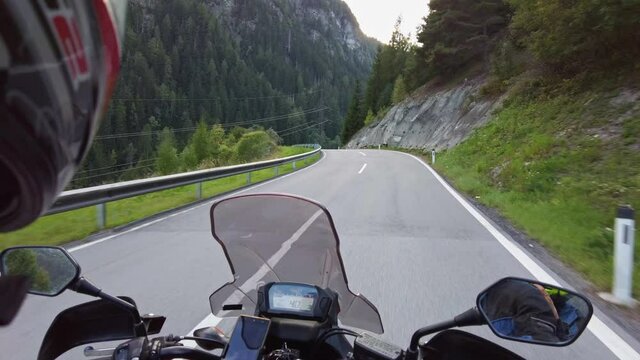 POV of Biker rides a motorcycle on a scenic mountain road in Austria. Steering wheel view. Motorcyclist on Motorbike goes on a Beautiful landscape highway. First-person view. Solo motorcycle travel.