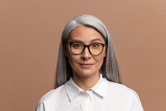 Portrait of cheerful positive businesswoman in white shirt smiling to camera, contented with life, charismatic individuality. Indoor studio shot isolated on beige background