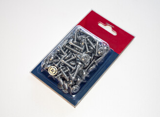 Fototapeta premium Self-tapping screws with a drill in a plastic package on a white table.