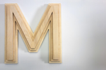 A three-dimensional letter M made of wood on a white isolate.