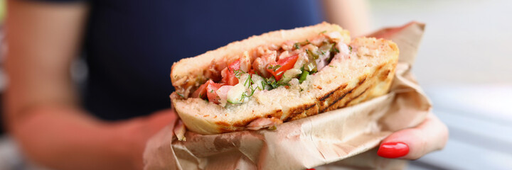 Woman holding a sandwich with filling in her hands