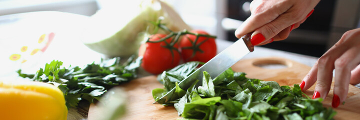 Woman cuts lettuce leaves with kitchen knife