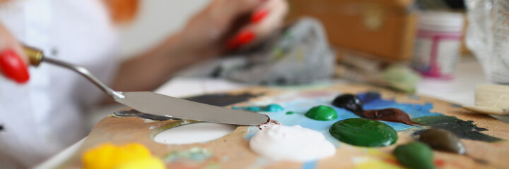 Obraz na płótnie Canvas Woman holding a spatula over a palette with paints