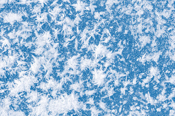 The textured surface of blue ice with white rime crystals. Winter seasonal background.