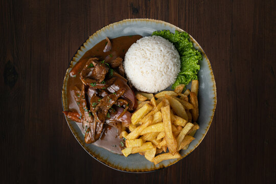 Peruvian dish Lomo saltado - beef tenderloin with purple onion, yellow chili, tomatoes served on plate with french fries and rice. Top view