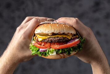 hands holding home made tasty burgers with grilled pork ribs on the wooden table. American food concept. fast food meal. banner, menu, recipe, place for text