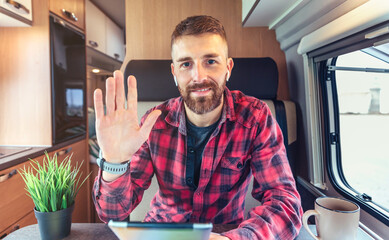 Man waving looking at camera on video call from his campervan