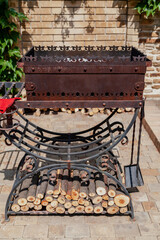 Forged brazier with firewood stands in yard