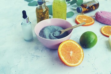 Blue clay, citruses, cream, herbal tinctures and aromatic oils in bottles, eucalyptus leaves on a light background, spa, natural ingredients