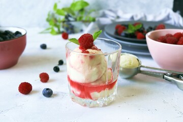 Fresh raspberries and blueberries, creamy ice cream poured with fruit syrup, light background, healthy food, natural dessert, home cooking 