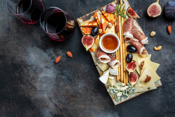 Appetizers table with italian antipasti snacks and wine in glasses. cheese, ham, nuts, fruit, bread sticks. Delicious balanced food concept. banner, menu, recipe place for text, top view