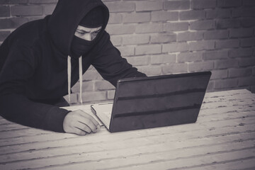 Anonymous hacker using laptop for stealing personal data from internet.
