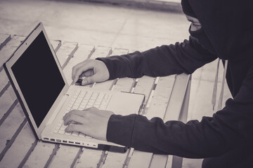 Anonymous hacker using laptop for stealing personal data from internet.