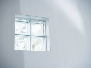 Close up four glass blocks, window bricks, lighted channel for the light through on the white wall background with copy space.